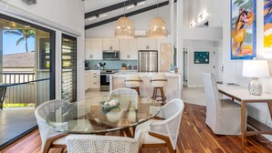 A modern kitchen with white cabinets, stainless steel appliances, and a dining area with wicker chairs and a glass table.