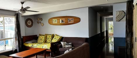 Una sala de estar con un sofá, una mesa de centro de madera y un ventilador de techo.