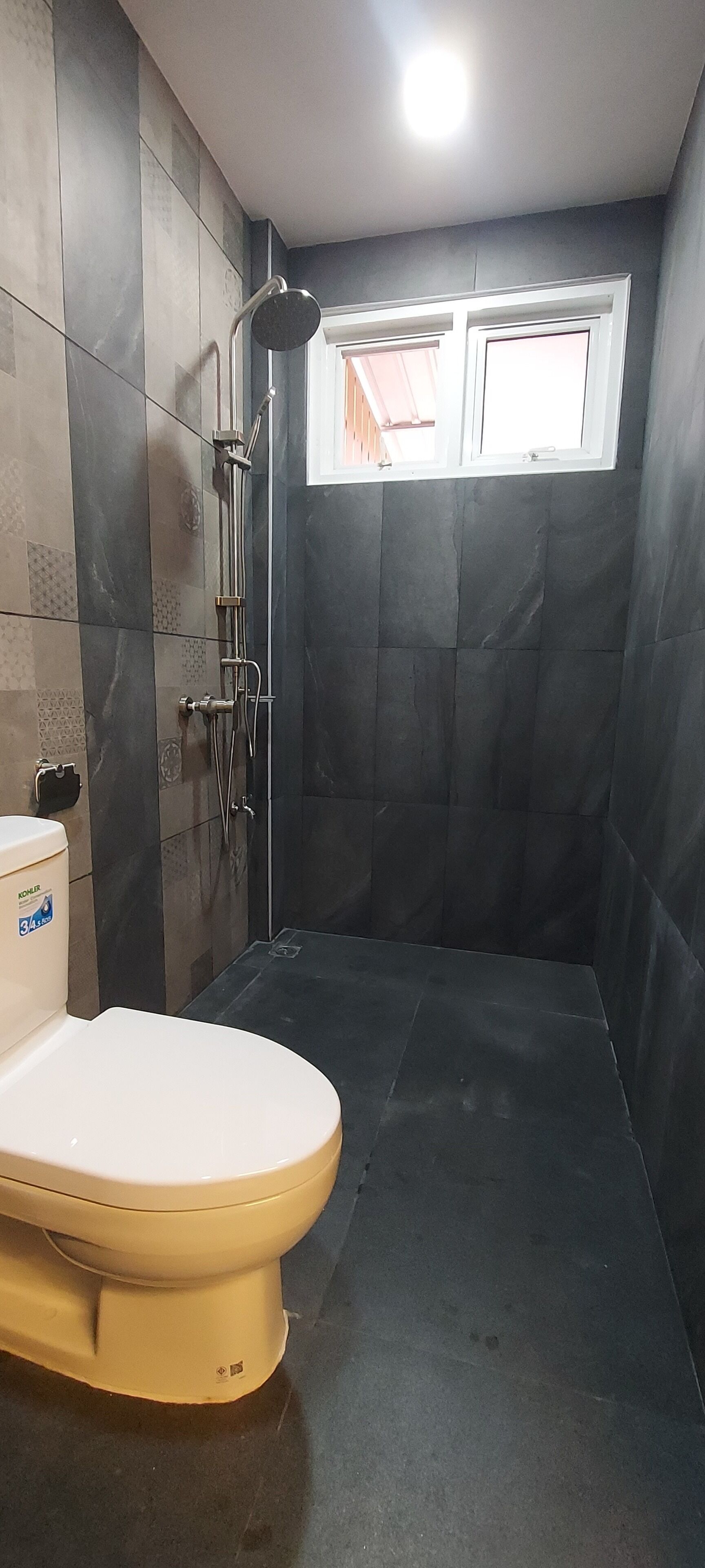 Un baño con inodoro, ducha y ventana.