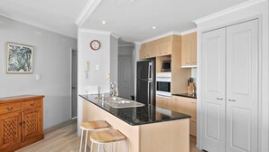 Une cuisine moderne dotée d’un îlot central, d’appareils électroménagers en acier inoxydable et de meubles de rangement en bois clair.