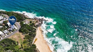 Vue aérienne d’une propriété située sur la côte, avec une plage, une route et des bâtiments.