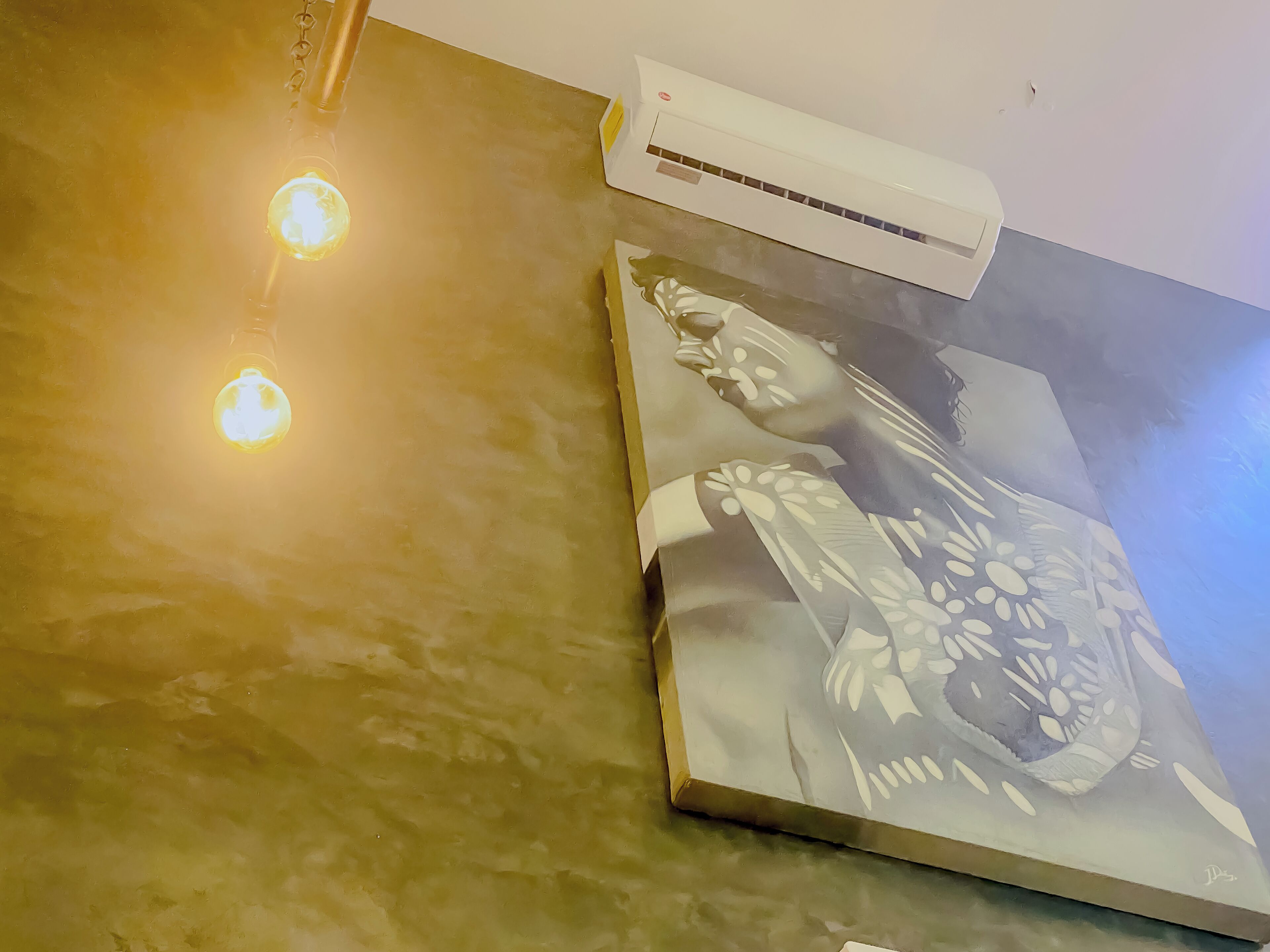 Una habitación con pared texturizada, un cuadro y un equipo de aire acondicionado.