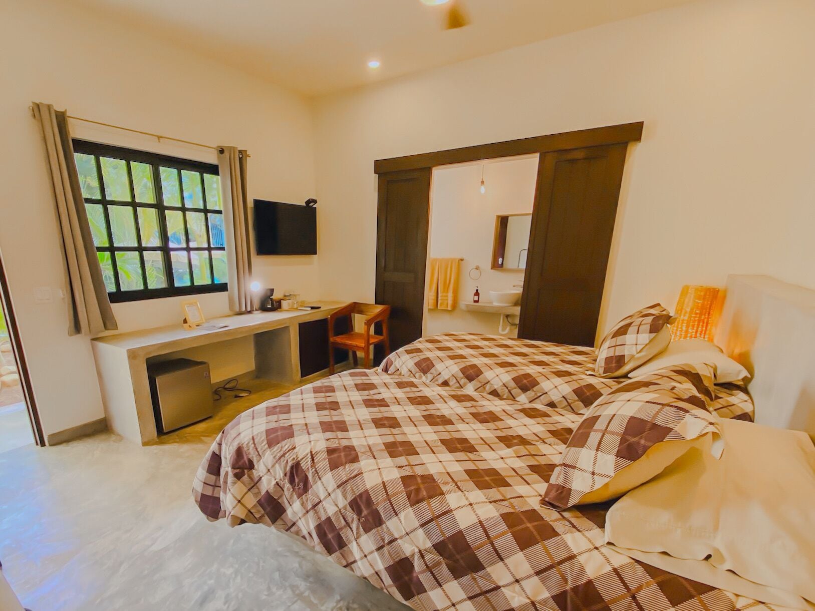 A bedroom with a bed, a desk, and a TV.
