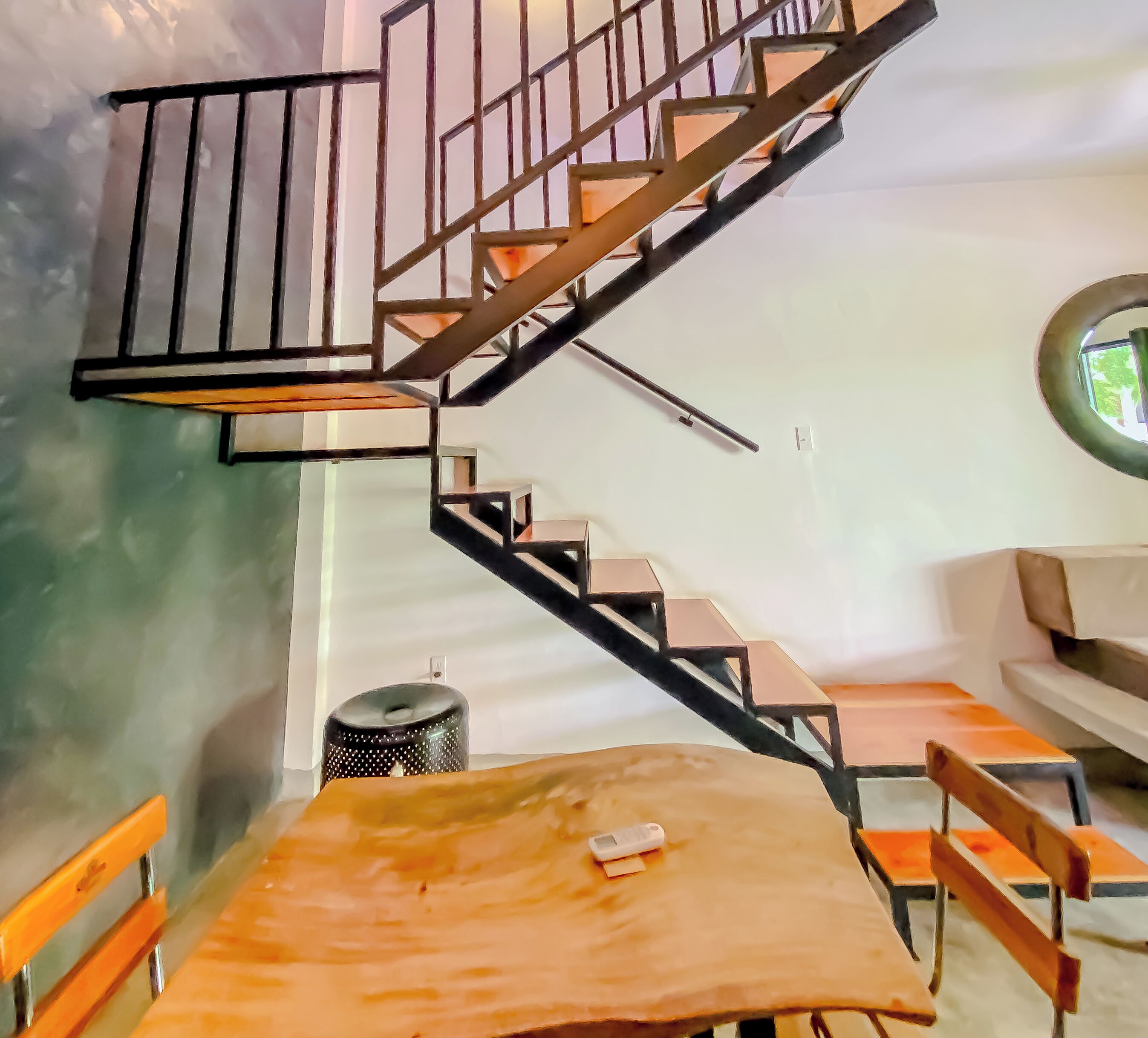 A modern interior with a spiral staircase, a round window, and a wooden table with chairs.
