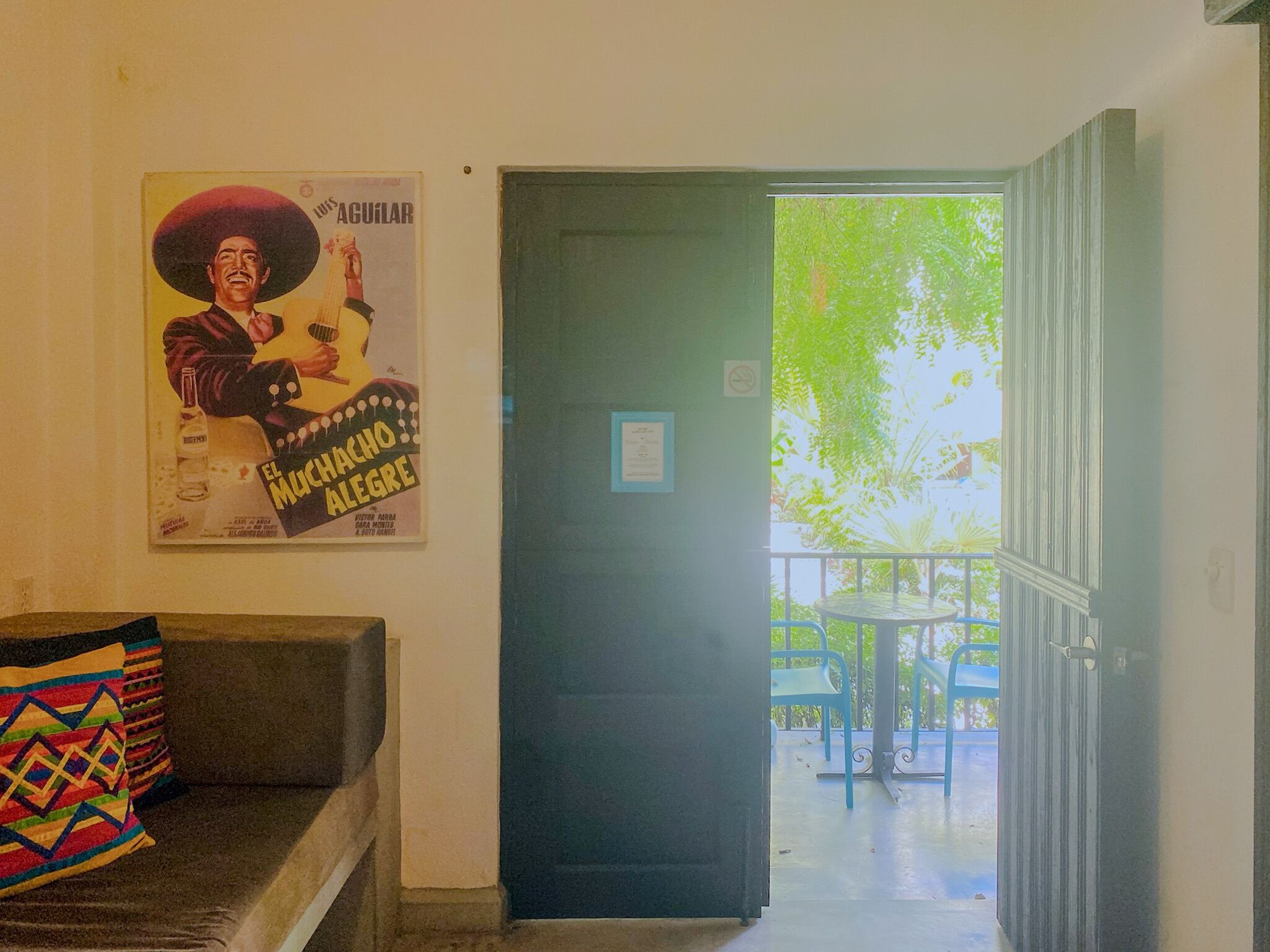 Une pièce avec une affiche, un canapé et une porte donnant sur un espace extérieur équipé d’une table et de chaises.