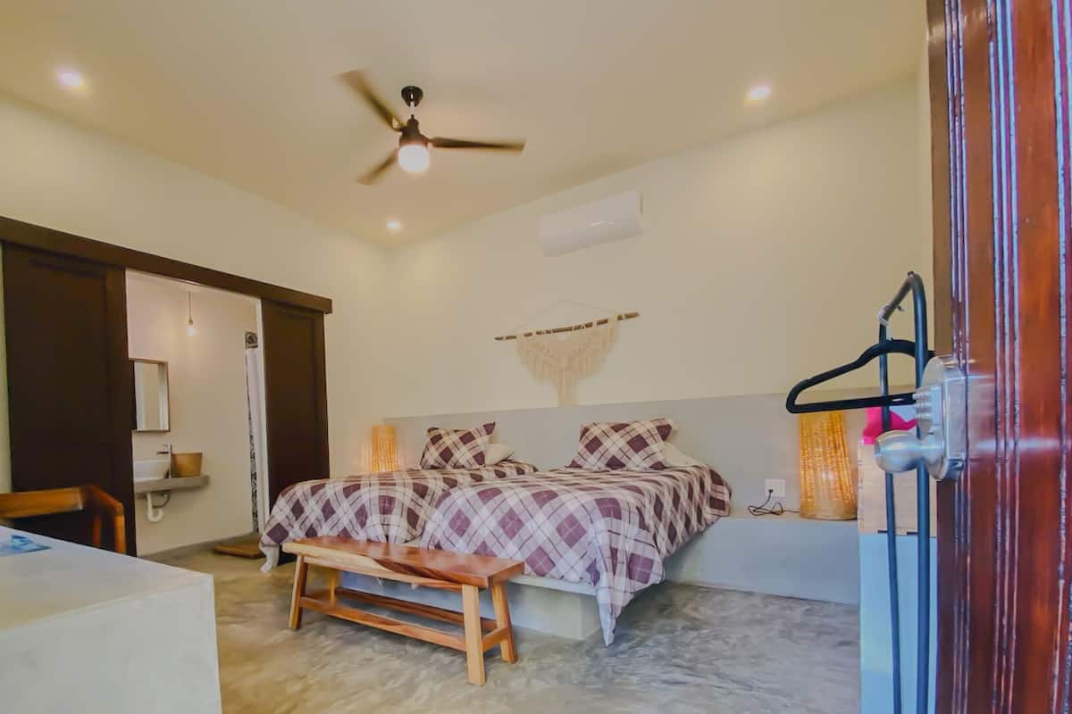 Une chambre à coucher comprenant un lit, un ventilateur de plafond, une table de chevet et un banc.