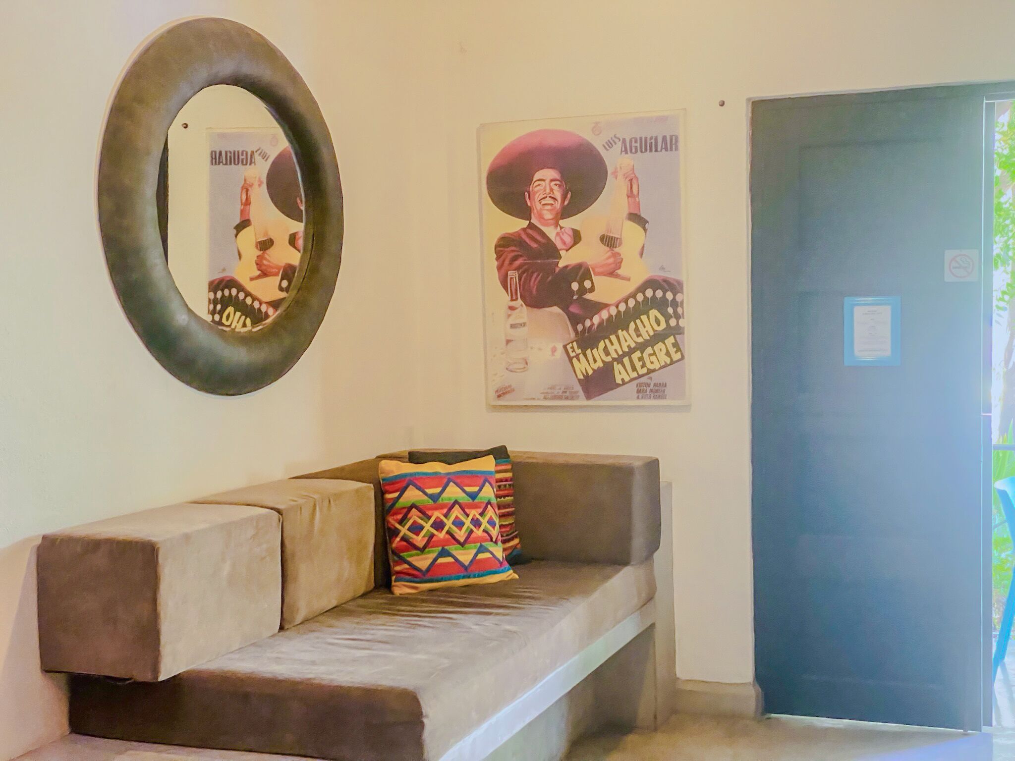 A room with a sofa, a mirror, and two movie posters on the wall.