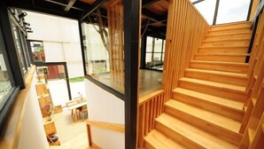 A modern interior with a wooden staircase, large windows, and a view of the outdoors. - Mumu Hotel (Dali City)
