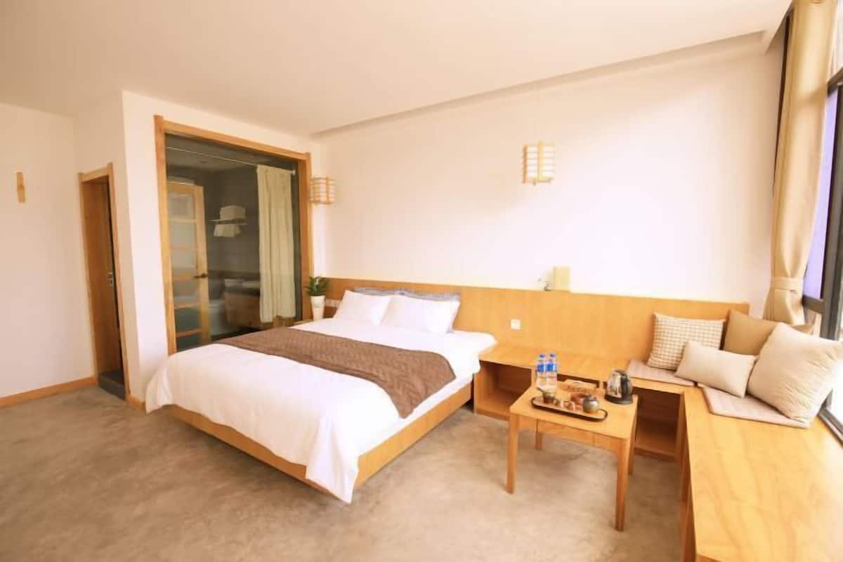 A hotel room with a bed, bedside table, and a seating area with a table and chairs.