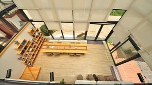 A modern interior with a long wooden table and chairs, a sofa, and a bookshelf. - Mumu Hotel (Dali City)
