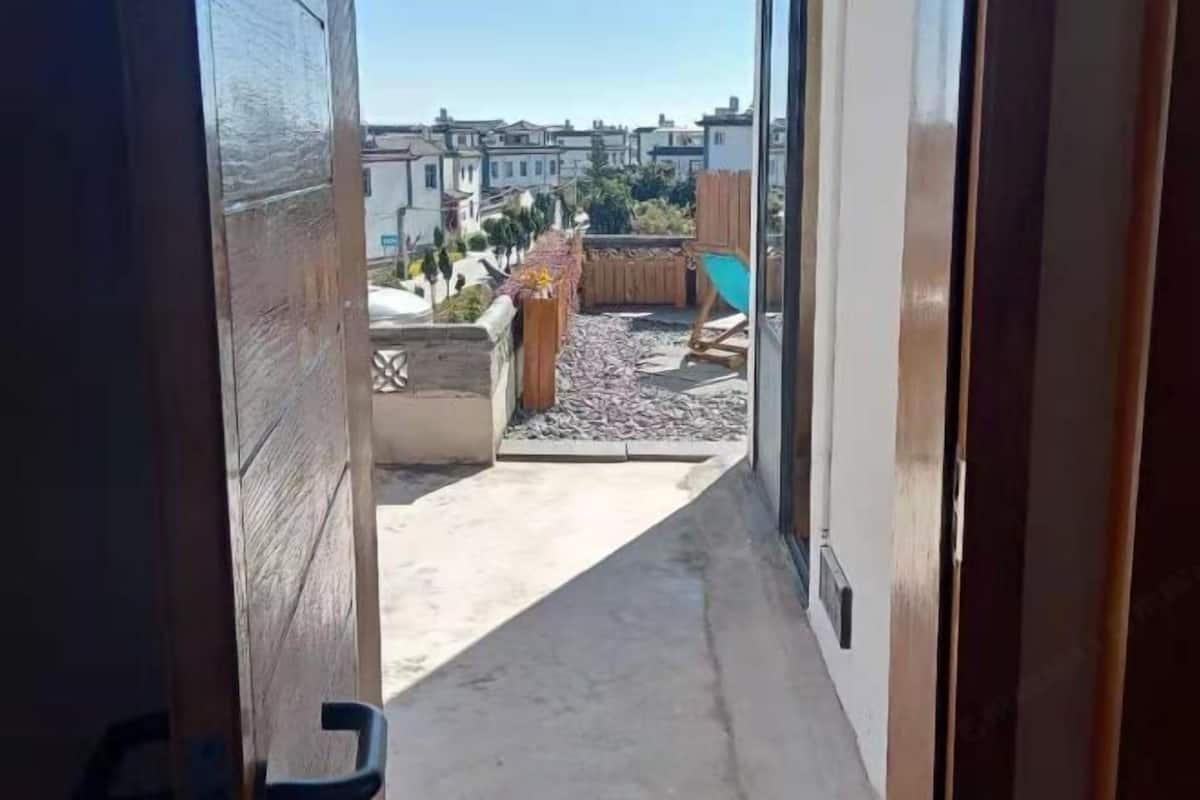 A narrow corridor leading to a rooftop terrace with a view of surrounding buildings.