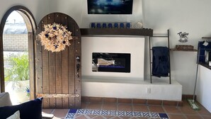 Una sala de estar con chimenea, televisor montado y una alacena estilo barra para café.