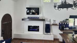 Una sala de estar con chimenea, televisión y candelabro.