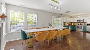 Una cocina amplia con una larga mesa de comedor, electrodomésticos modernos y grandes ventanales.