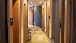 A hotel hallway with wooden doors, a carpeted floor, and a patterned carpet runner. - Xima Hotel (Taizhou West Station Branch) (Taizhou)