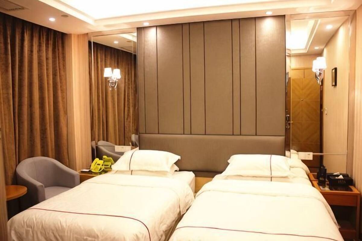 Habitación de hotel con dos camas, una silla, un escritorio, un espejo y una cortina.
