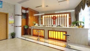 A hotel reception area with a marble counter, wooden paneling, and a red decorative element above the counter. - Xima Hotel (Taizhou West Station Branch) (Taizhou)