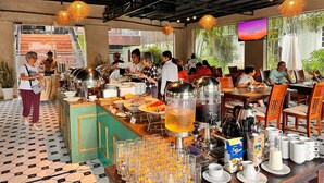 A buffet setup with various food items and beverages, a television screen, and a seating area with tables and chairs.