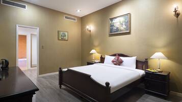 Una camera d'albergo con un letto grande, comodini con lampade, un quadro appeso e una porta che dà su un bagno.