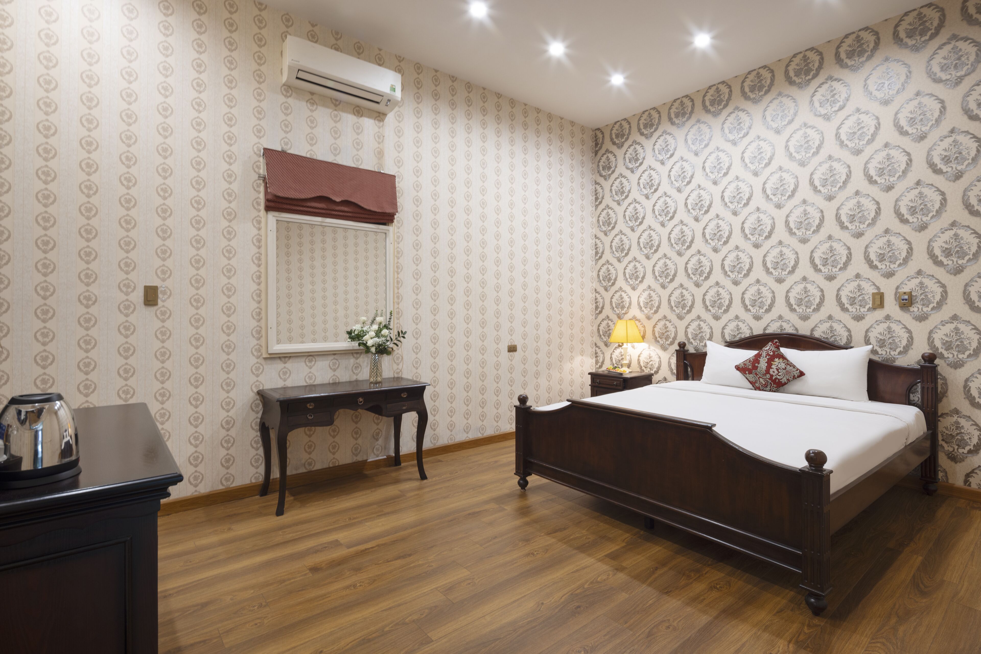 A bedroom with a wooden bed, a nightstand, a desk, and an air conditioning unit.