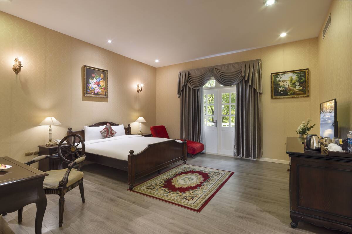 Een hotelkamer met een bed, bureau, stoel en uitzicht op het buiten door een deur.