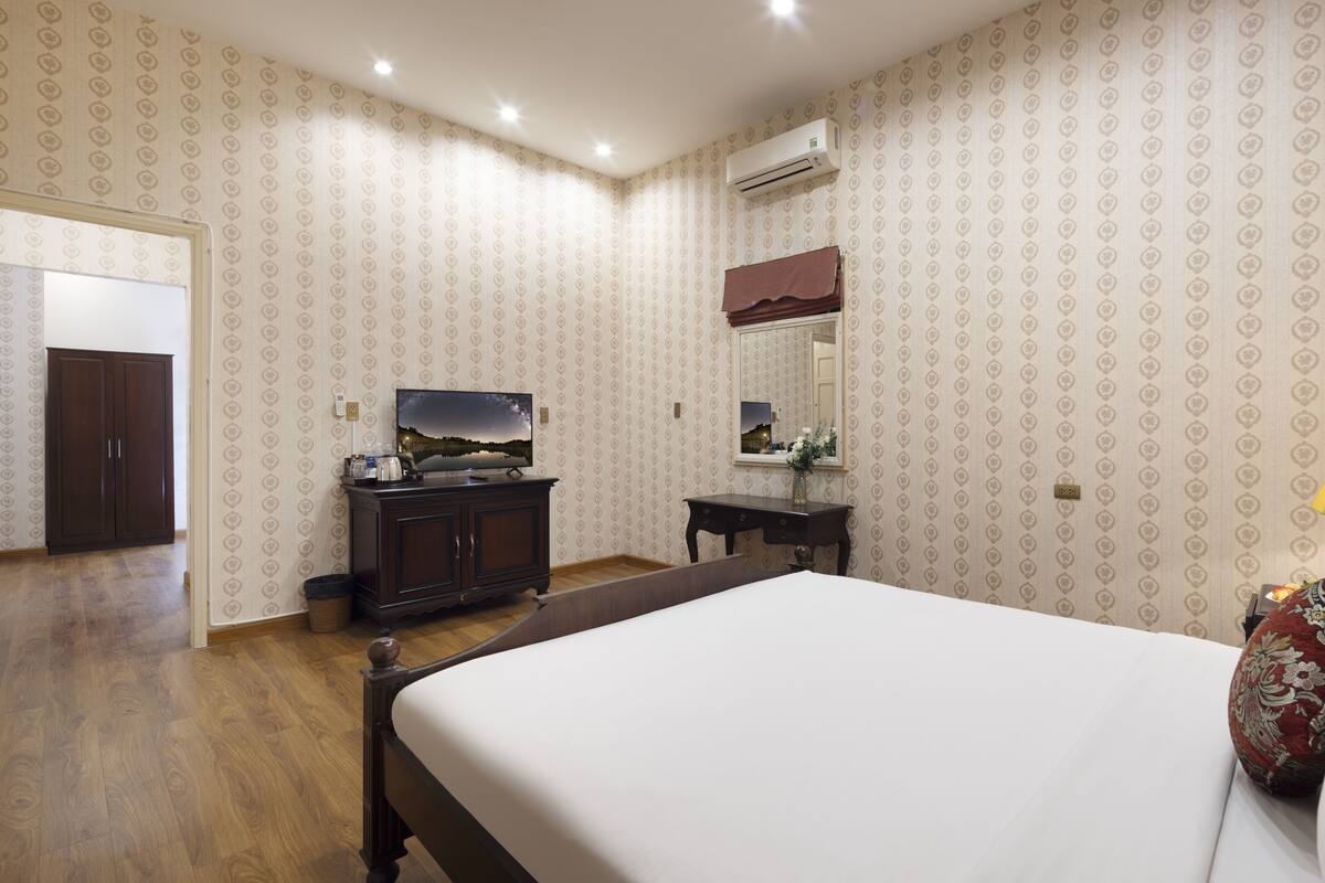 Een hotelkamer met een groot bed, een dressoir, een televisie en een spiegel.