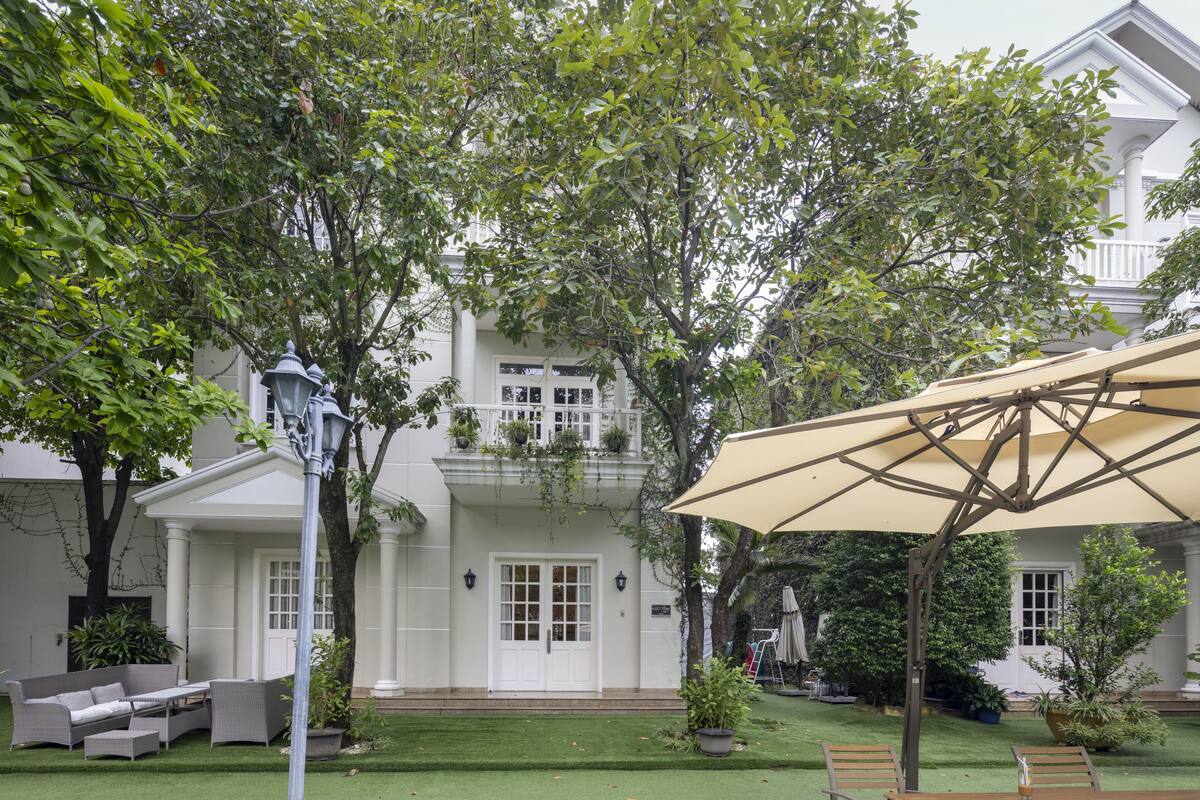Een goed onderhouden tuin met gazon, tuinmeubilair en een grote parasol.