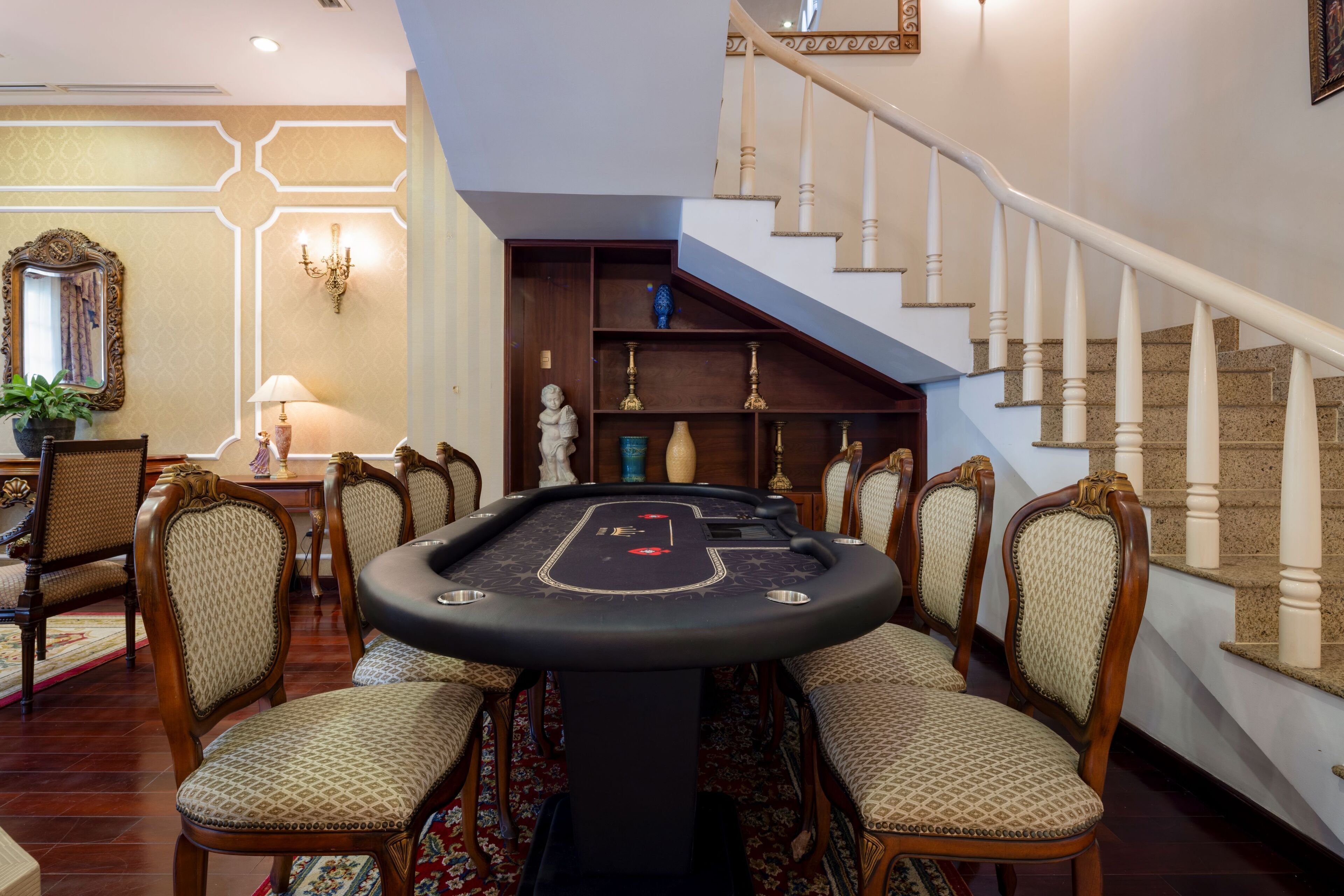 A room with a pool table, chairs, a staircase, and a chandelier.
