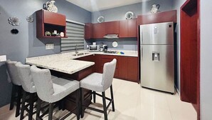 A compact kitchen with a central island, built-in appliances, and a dining area with four chairs.