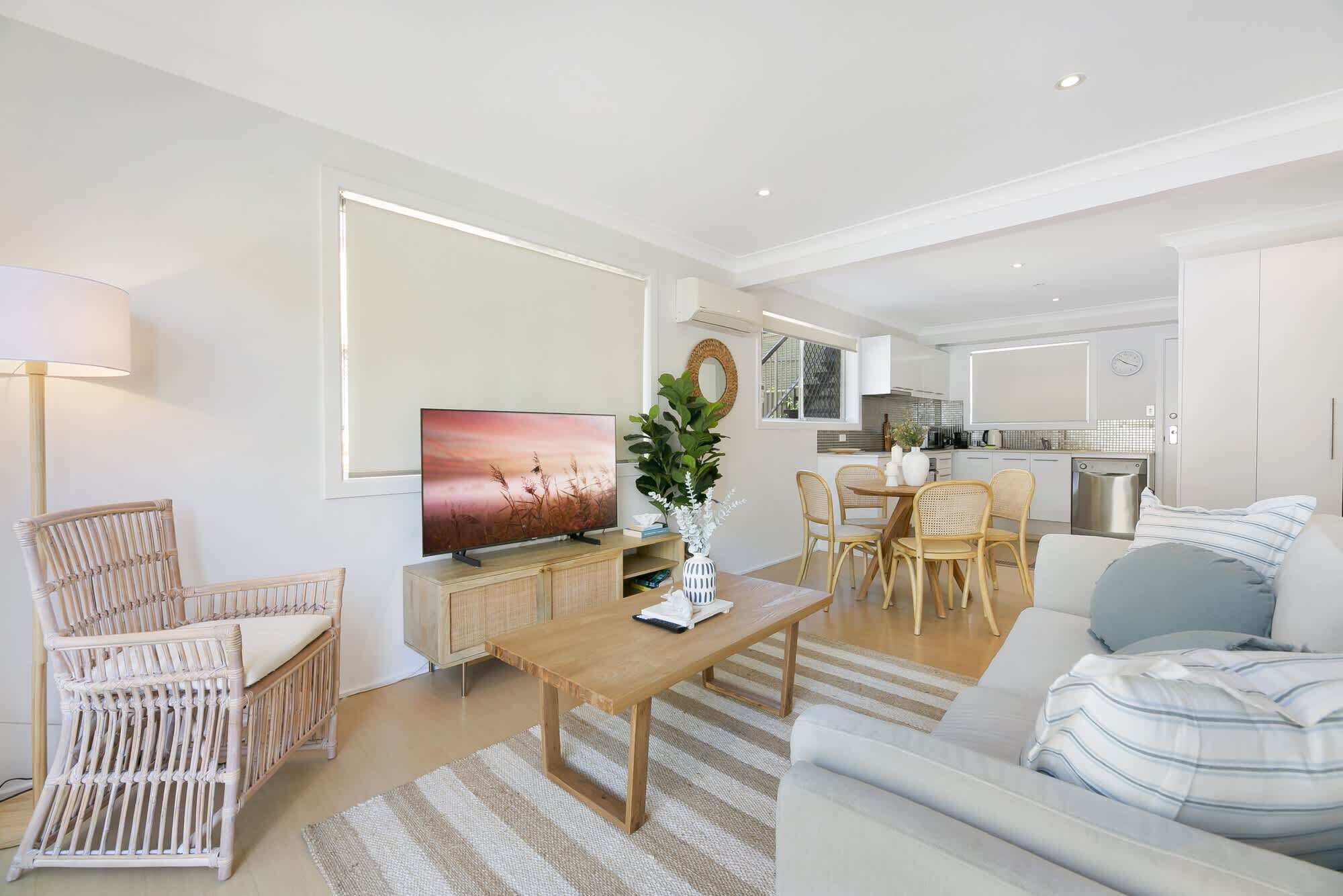 Una sala de estar moderna con televisión, comedor y cocina.