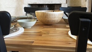 Un coin repas avec une cheminée en briques, une table en bois et des chaises noires.