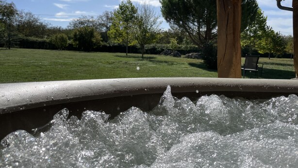 Un bain à remous avec vue sur une pelouse verdoyante et des arbres.