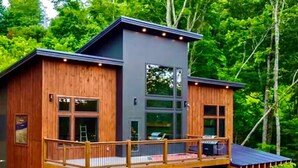 A cabin with a wooden exterior, a balcony, and a large window. - Take A Dip Lodge - Indoor Heated Pool (Sevierville)