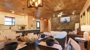 A cozy interior with a wooden dining table set for two, a stone fireplace, and a comfortable seating area with a sofa and chairs. - Indoor Pool Cabin, Theater, 7 mi to Dollywood (Pigeon Forge)