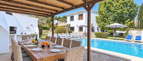 An outdoor dining area with a pool, wicker furniture, and a covered patio.