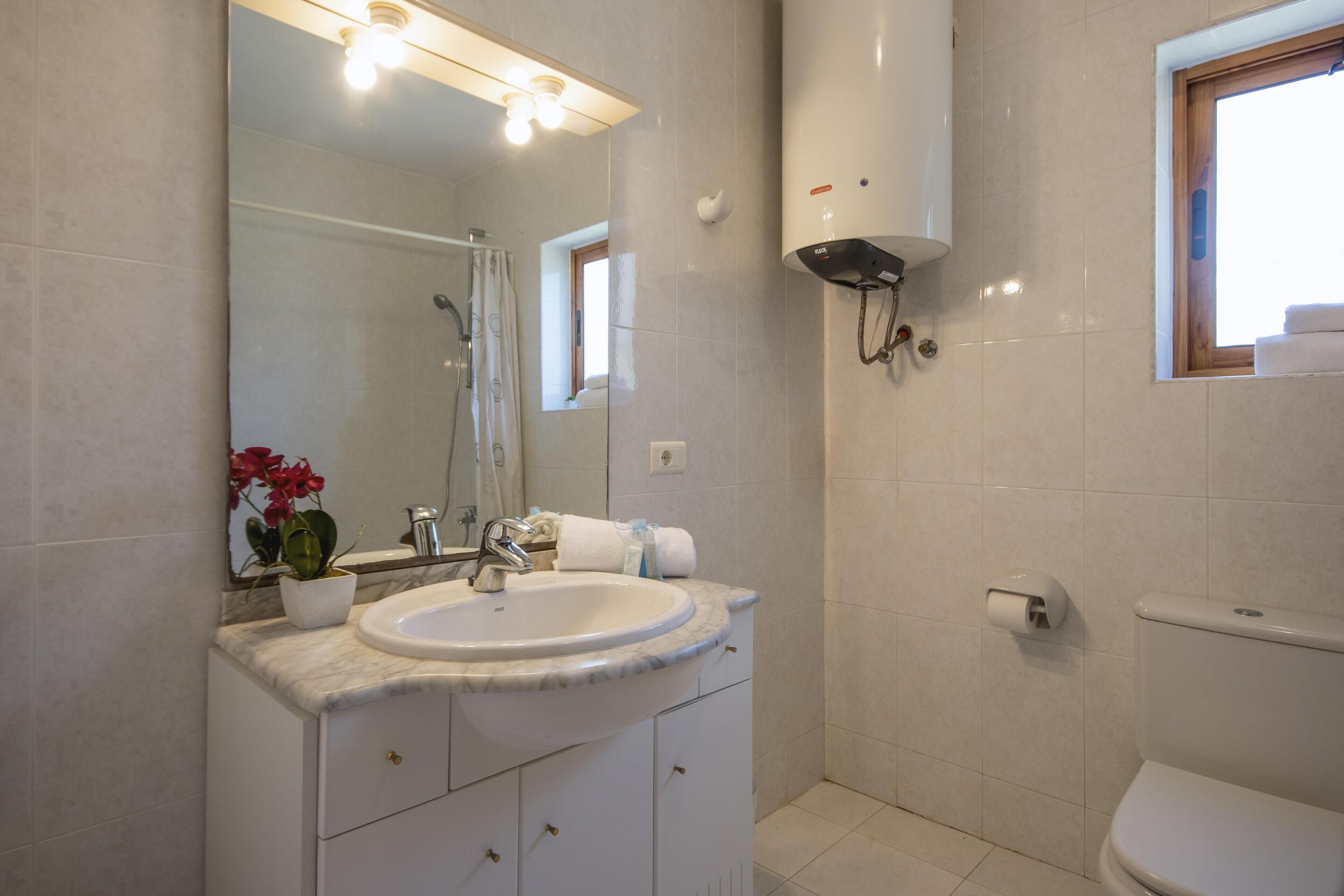 Une salle de bain avec un lavabo blanc, un miroir et des toilettes.