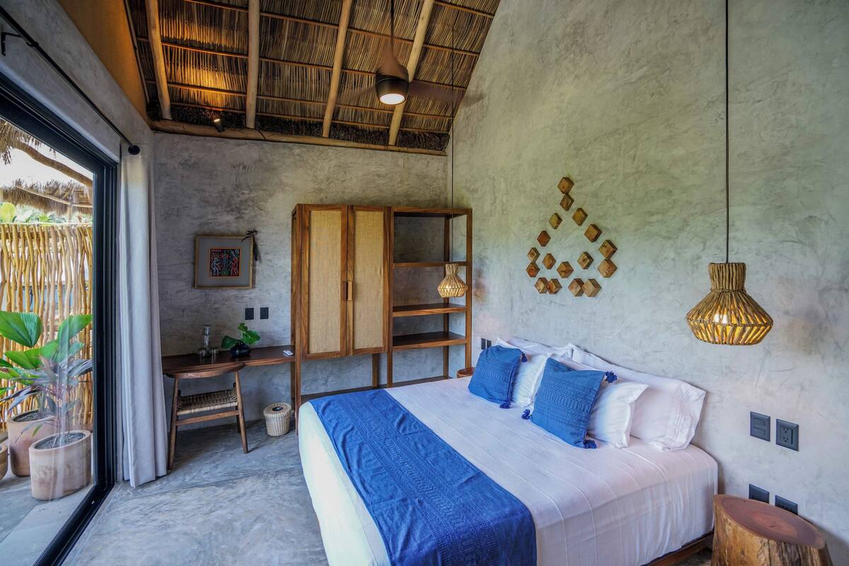 Un dormitorio con cama, escritorio y vistas al exterior.