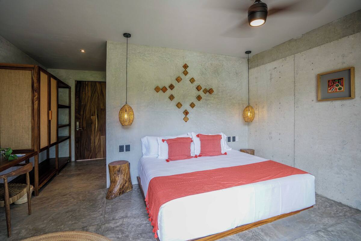 Un dormitorio con una cama grande, muebles de madera y una pared de concreto con un diseño geométrico.