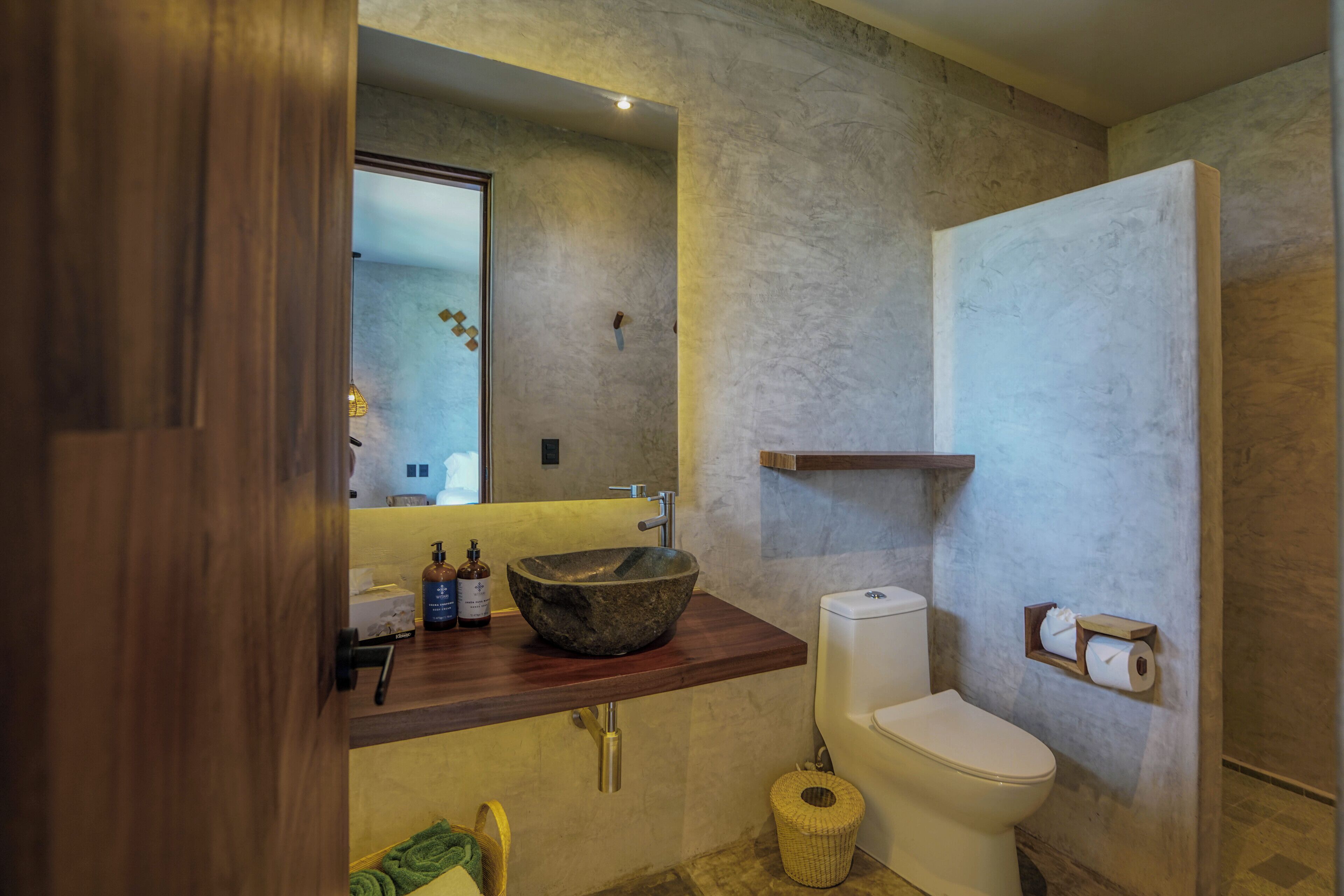 A bathroom with a wooden vanity, a stone sink, a toilet, and a towel rack.