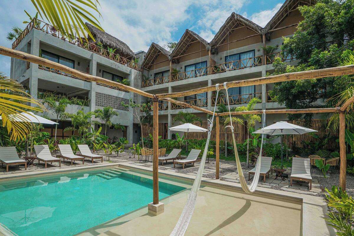 Un resort con piscina, sillas de descanso y una hamaca.