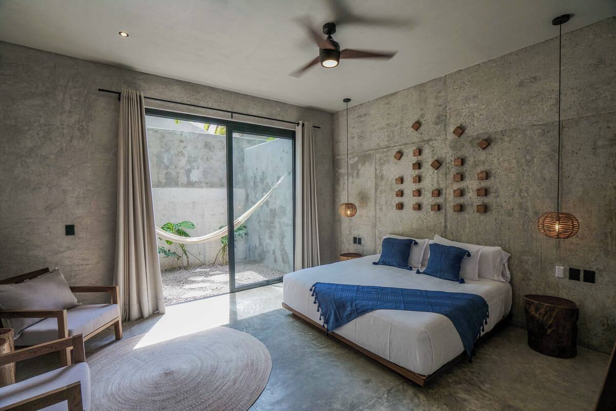 Un dormitorio moderno con una cama grande, una hamaca y vistas a un jardín.