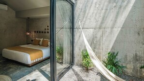 A modern bedroom with a large bed, a glass partition, and a hammock.
