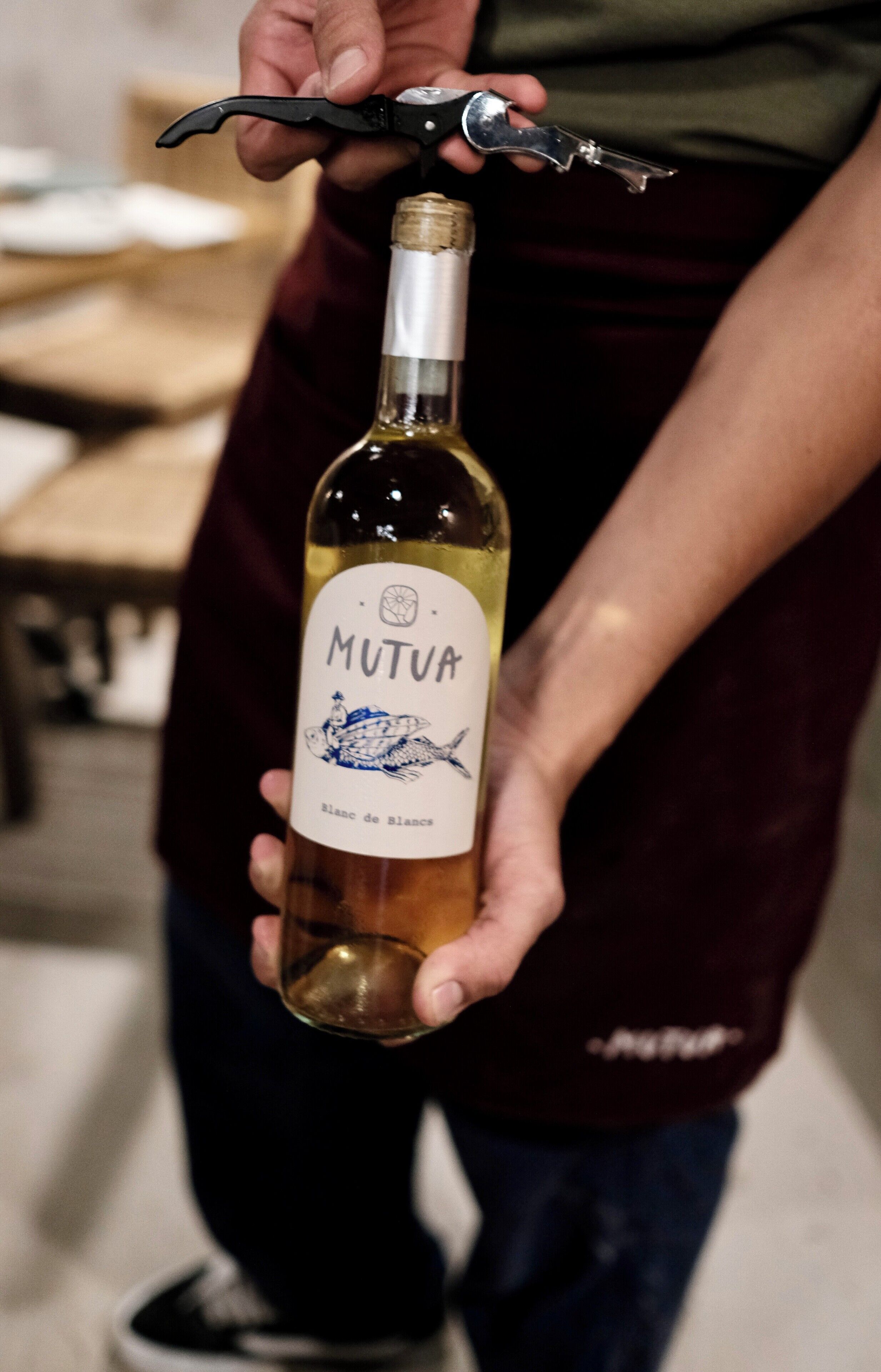 Une personne tenant une bouteille de vin et un tire-bouchon.