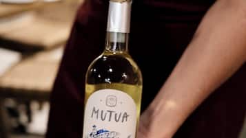 Une personne tenant une bouteille de vin et un tire-bouchon.