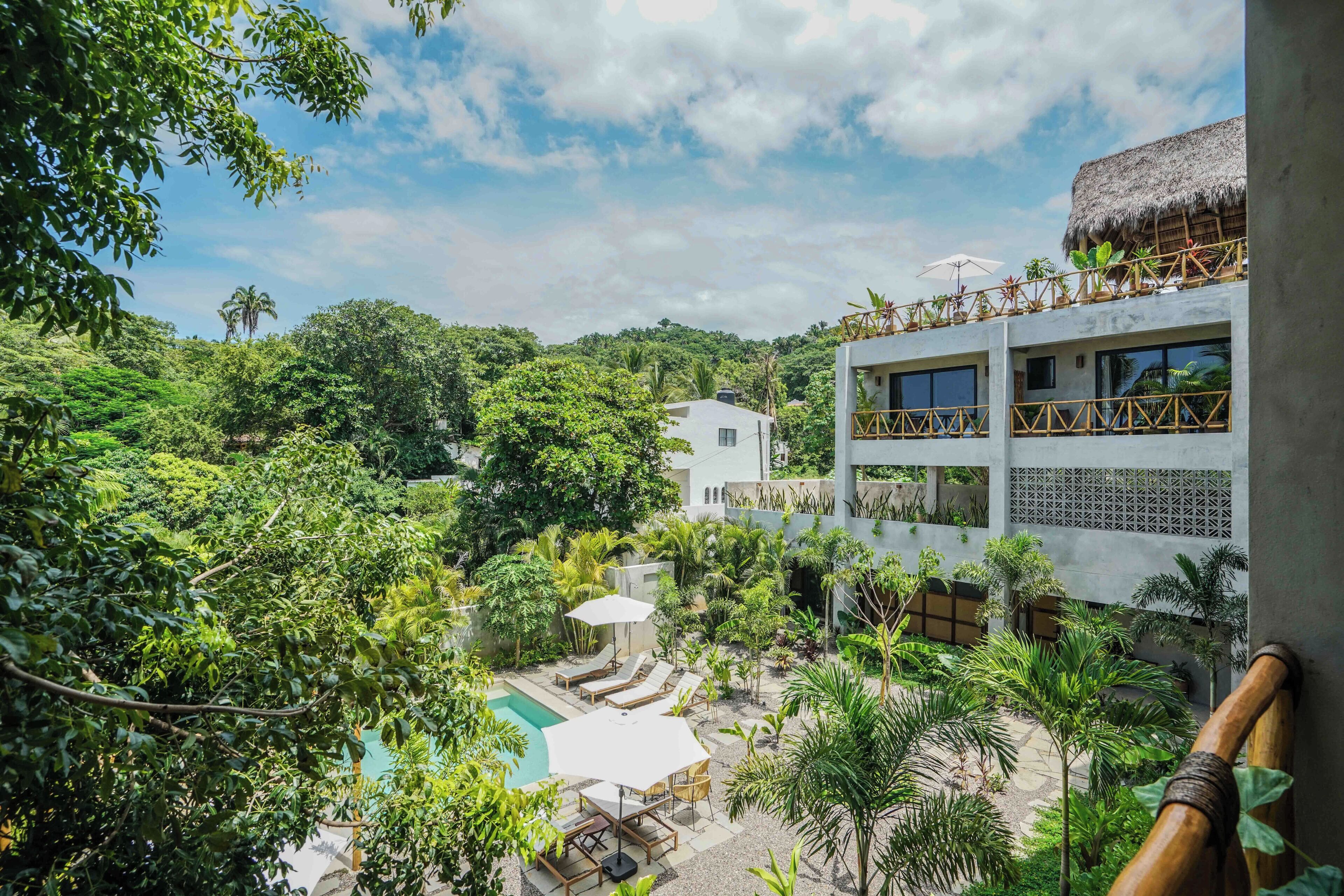 Um resort com piscina, espreguiçadeiras e vegetação exuberante.