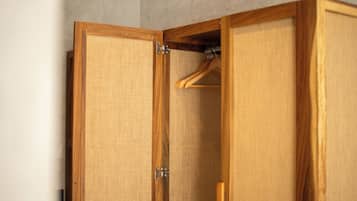 A wooden wardrobe with a fabric interior and a wooden hanger inside.