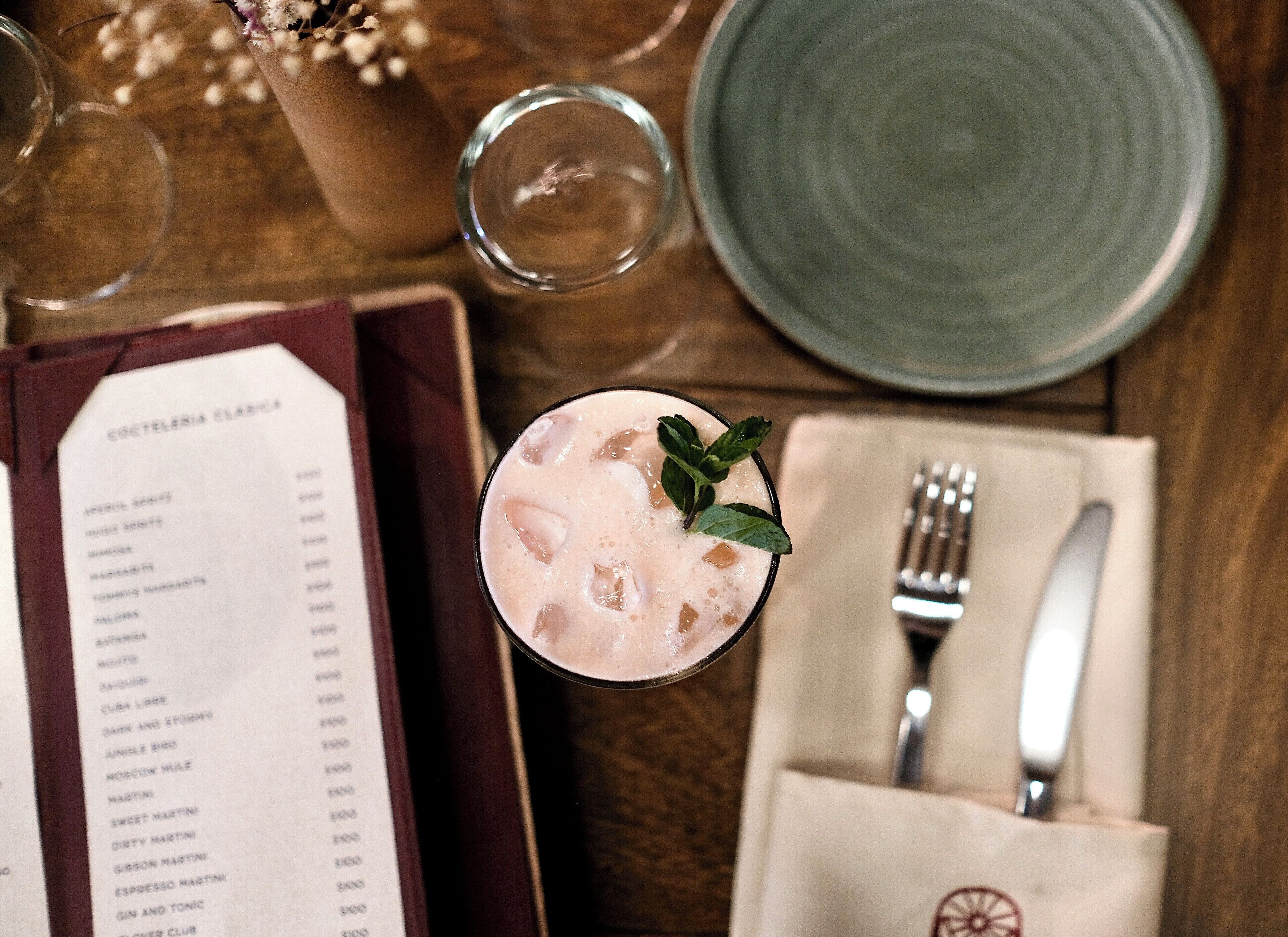 Un menu et une boisson dans un verre, posés sur une table en bois.