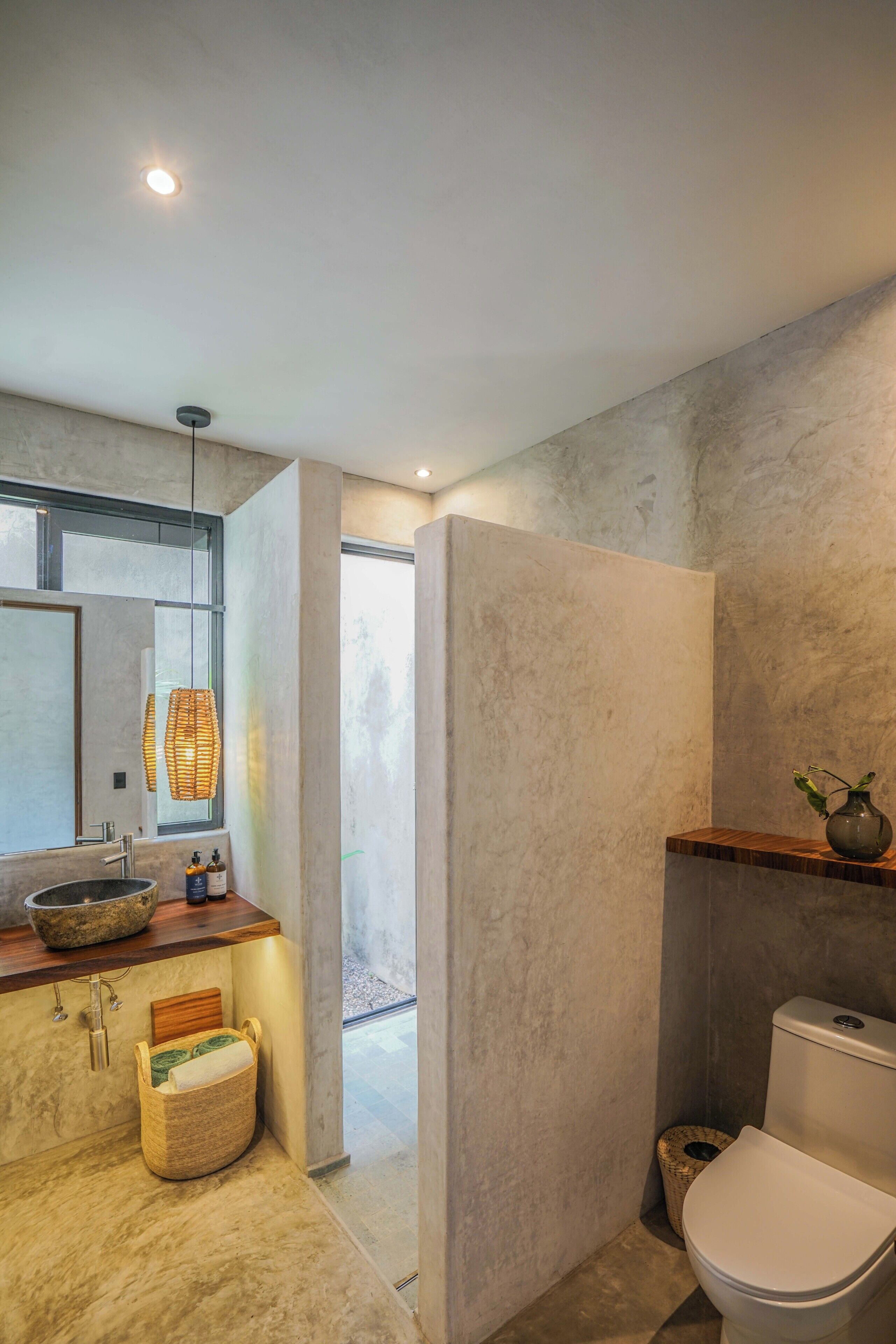 A modern bathroom with a large mirror, a wooden countertop, a white toilet, and a shower area.