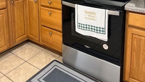 A kitchen with wooden cabinets, a stainless steel microwave, a stove, and a coffee maker.