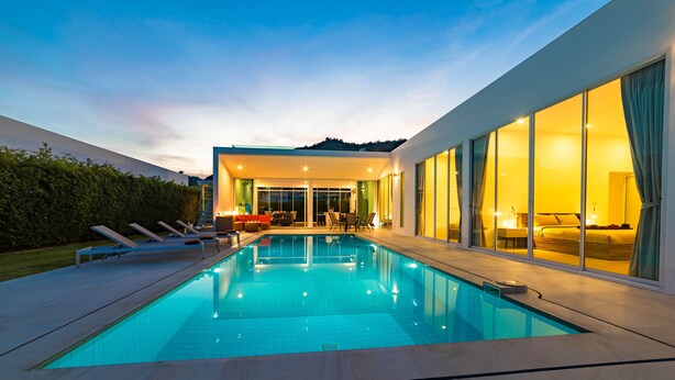 A modern house with a swimming pool, large windows, and a well-lit interior. - Modern 4 Bedroom Pool Villa - KHA5 (Hua Hin)